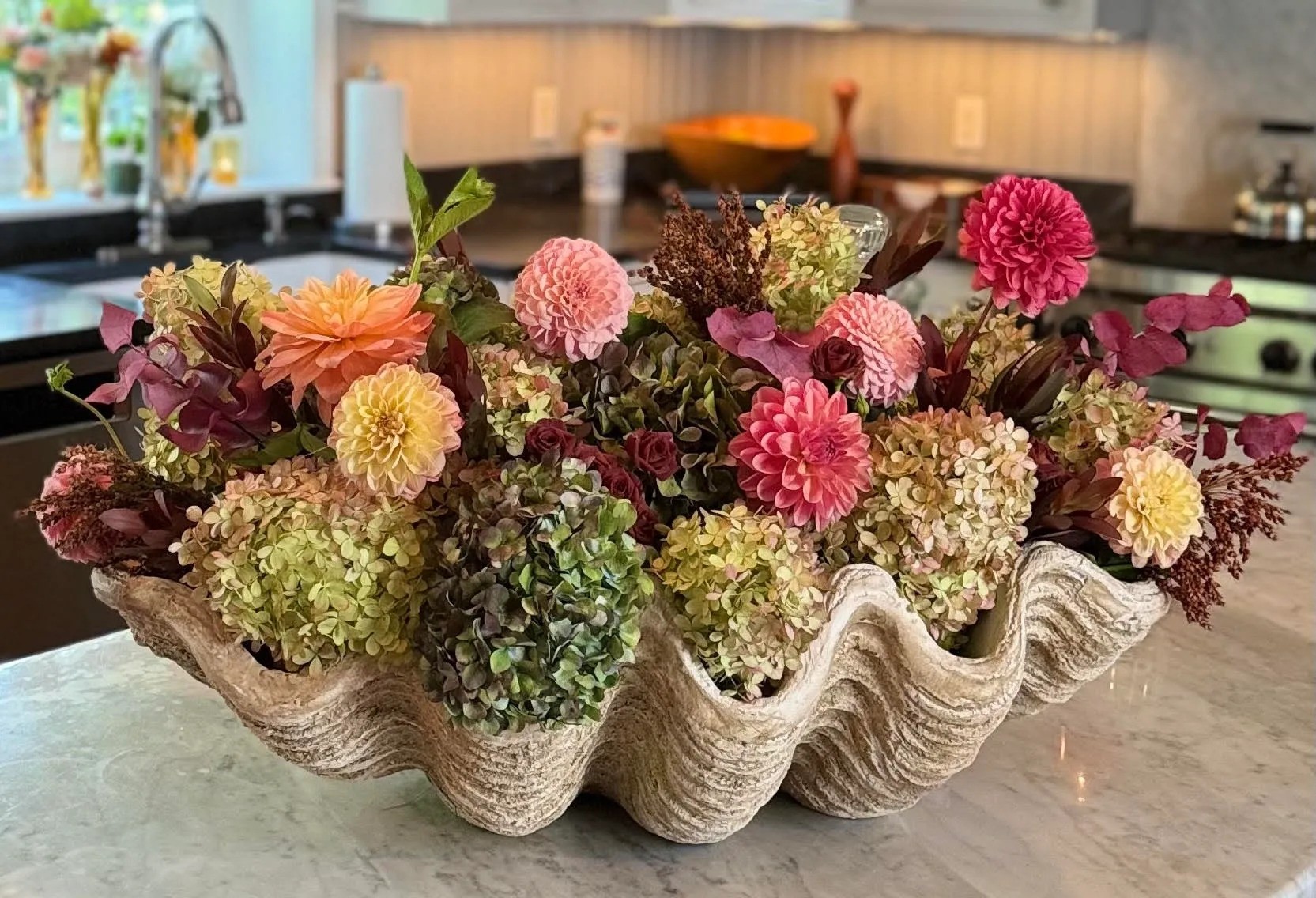A vibrant assortment of flowers arranged in a shell bowl