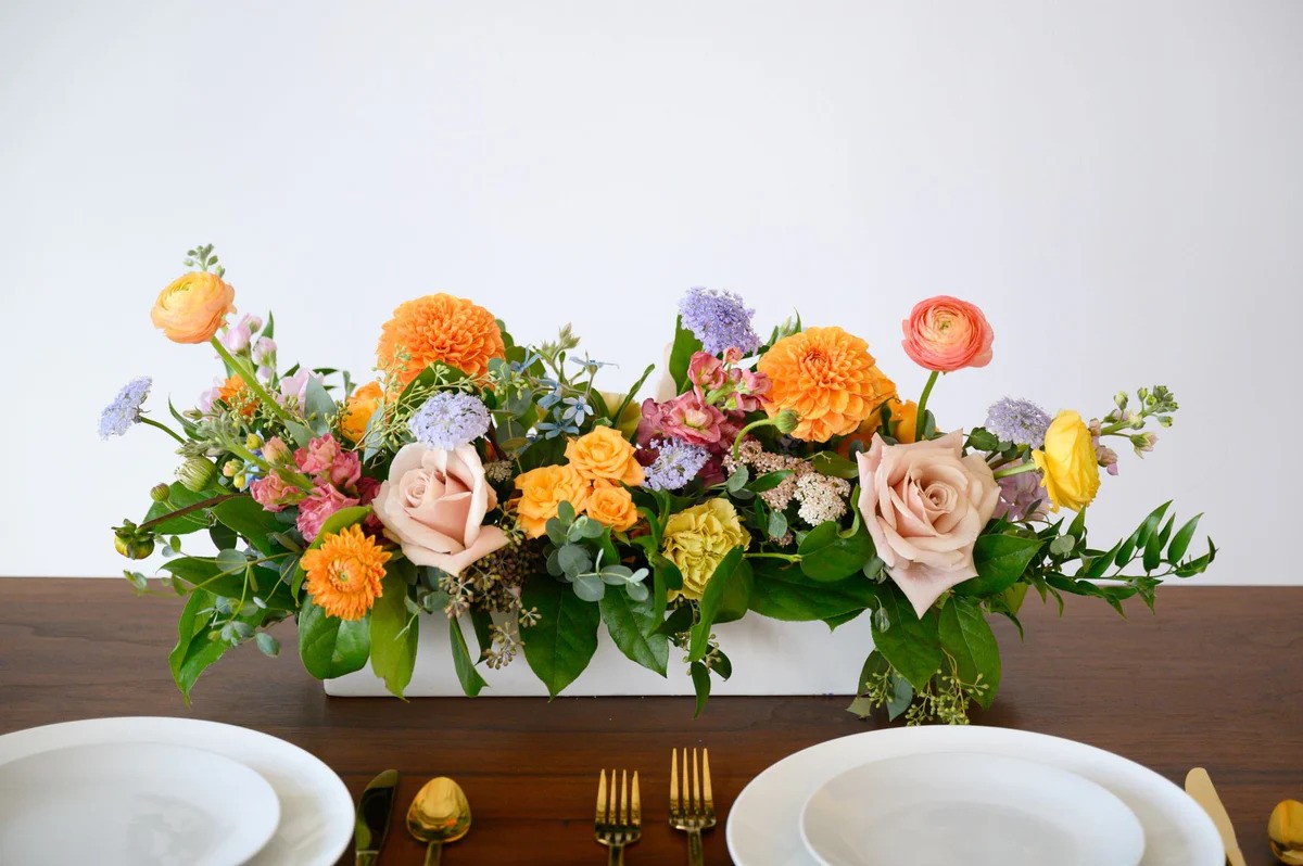 A dining table set with white plates and elegant gold forks and knives